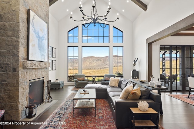 living room featuring a chandelier, high vaulted ceiling, a stone fireplace, a mountain view, and dark wood-type flooring