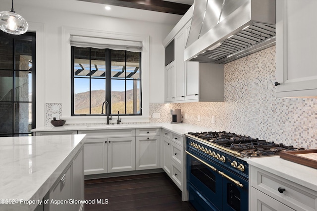 kitchen with a mountain view, a sink, exhaust hood, double oven range, and pendant lighting