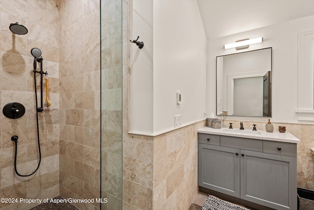 bathroom with wainscoting, tile walls, vanity, and walk in shower