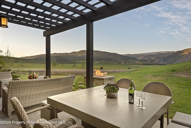 view of patio with an outdoor fire pit, a rural view, a mountain view, a pergola, and outdoor dining space