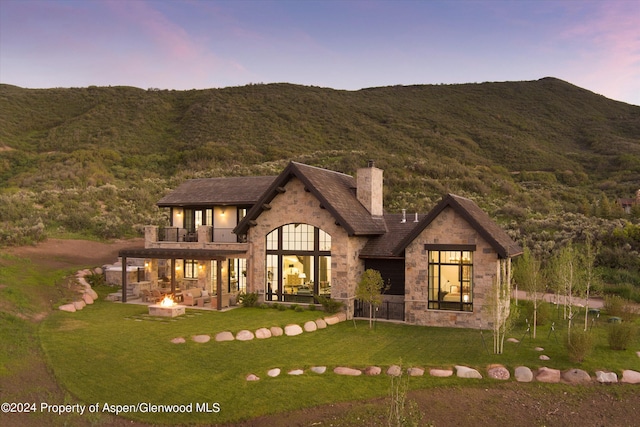 view of front of house with an outdoor fire pit, stone siding, and a mountain view