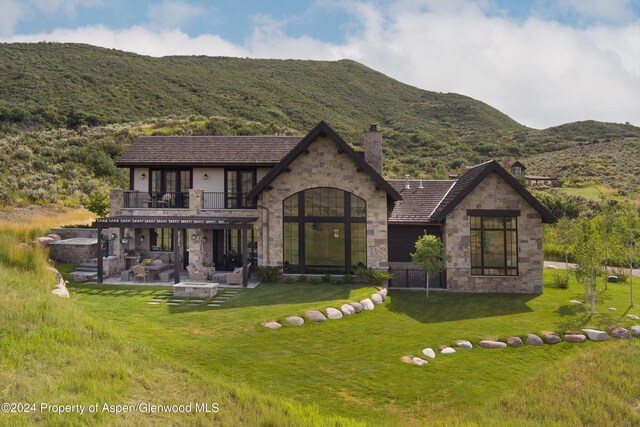 view of front of property featuring a patio, stone siding, a mountain view, and a front yard