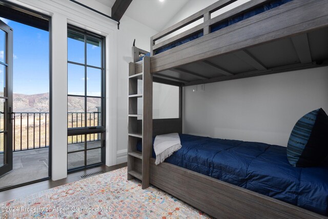 unfurnished bedroom featuring vaulted ceiling, visible vents, a mountain view, and wood finished floors