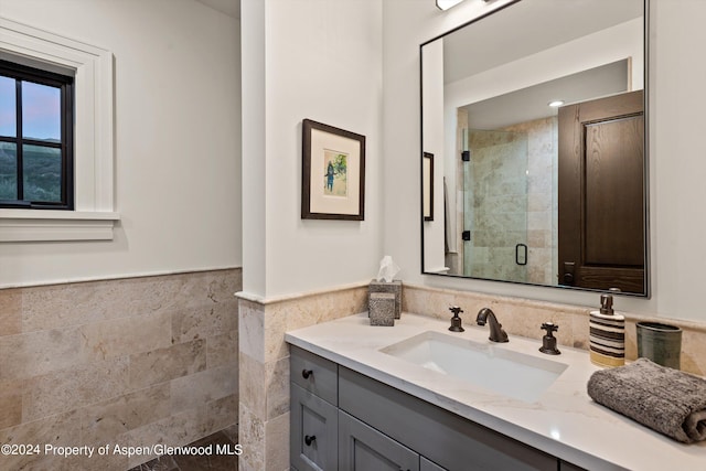 bathroom with a stall shower, a wainscoted wall, tile walls, and vanity