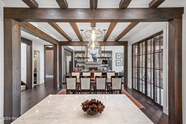 dining room featuring dark wood-style floors, beam ceiling, and a fireplace