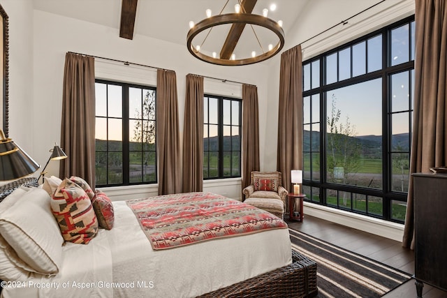 bedroom with vaulted ceiling with beams, wood finished floors, and a notable chandelier