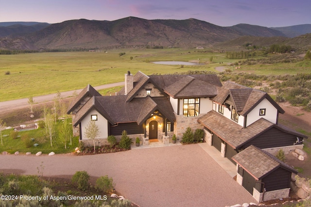 view of front facade featuring stone siding, a mountain view, and driveway