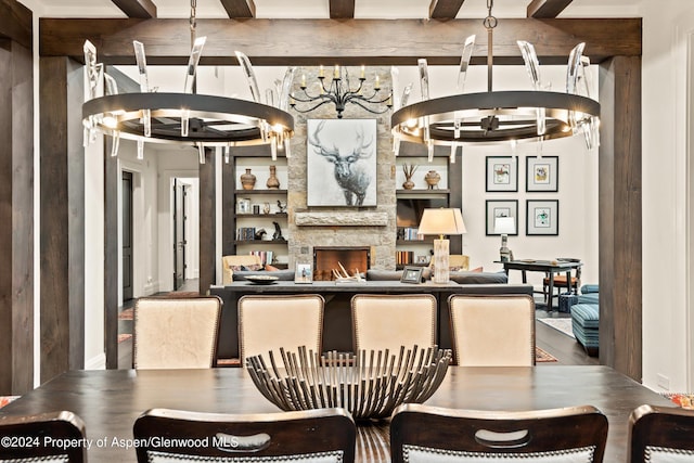 dining space featuring a stone fireplace, beamed ceiling, built in shelves, and a notable chandelier