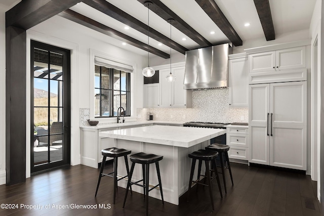 kitchen featuring pendant lighting, white cabinets, and wall chimney range hood