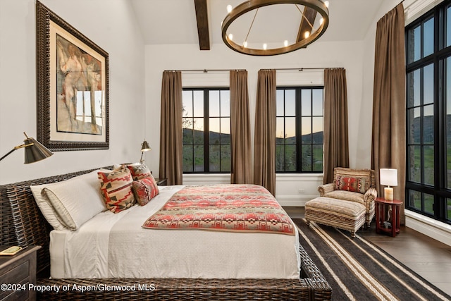 bedroom featuring lofted ceiling with beams, baseboards, wood finished floors, and a notable chandelier