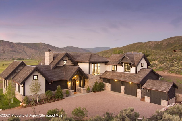 view of front of home with a mountain view, stone siding, driveway, stucco siding, and a chimney