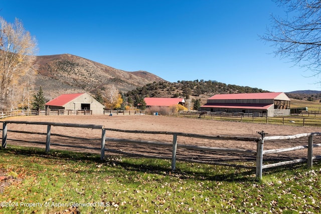 view of yard with an exterior structure, a rural view, an enclosed area, and a mountain view