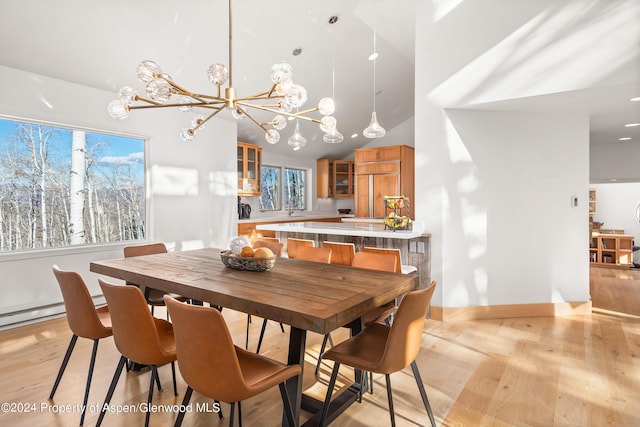 dining room with high vaulted ceiling, light hardwood / wood-style flooring, a notable chandelier, and sink