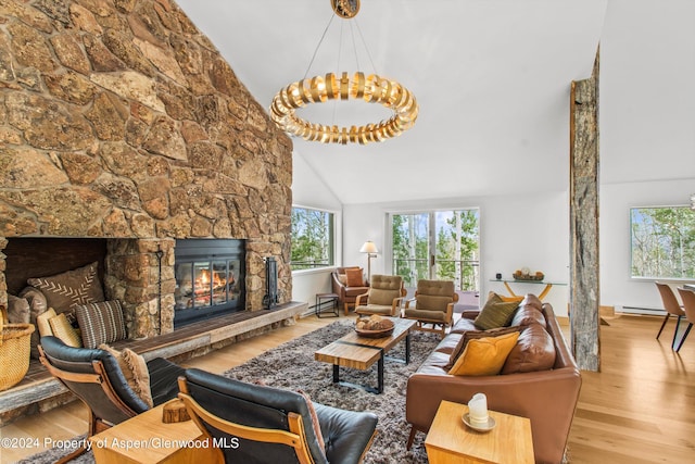 living room with a fireplace, high vaulted ceiling, a chandelier, and light hardwood / wood-style flooring