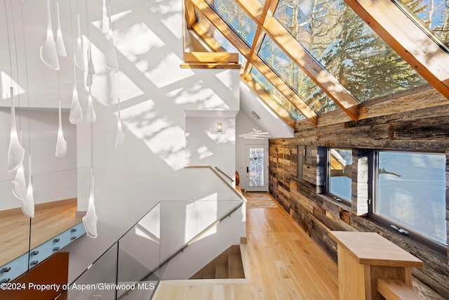 interior space with beam ceiling, high vaulted ceiling, a healthy amount of sunlight, and light hardwood / wood-style floors