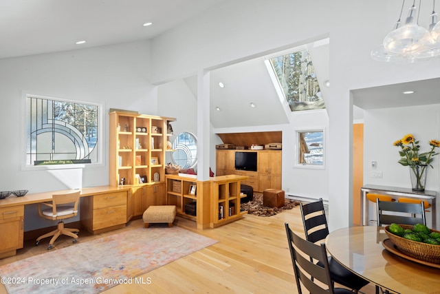 office area with built in desk, high vaulted ceiling, and light hardwood / wood-style flooring