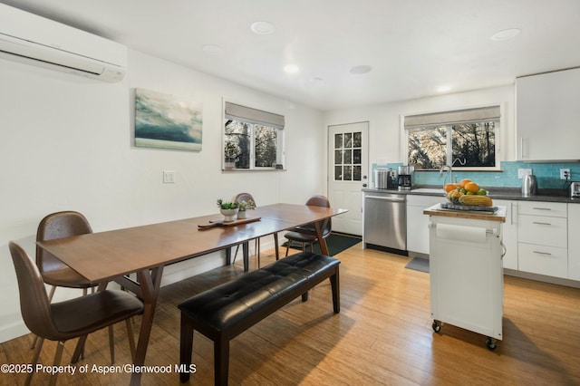 dining space with a wall mounted AC, light hardwood / wood-style floors, and sink