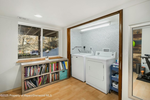 clothes washing area featuring washer and dryer and light wood-type flooring