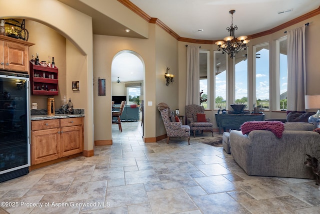 759 36 3/10 Rd, Palisade, CO 81526 - living room featuring beverage cooler, healthy amount of natural light, a chandelier, stone tile flooring, and ornamental molding