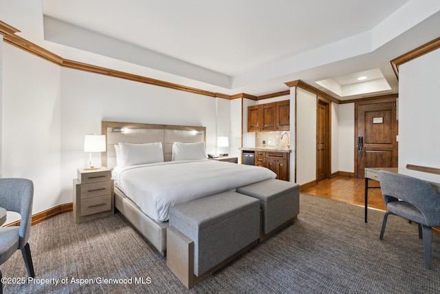 bedroom featuring wood-type flooring, sink, and a tray ceiling