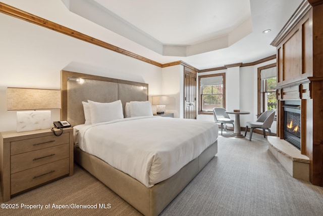 carpeted bedroom with crown molding and a tray ceiling
