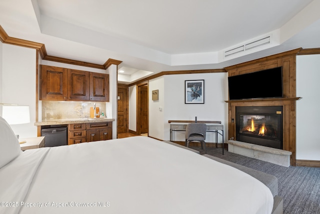 bedroom with a large fireplace, ornamental molding, and a raised ceiling