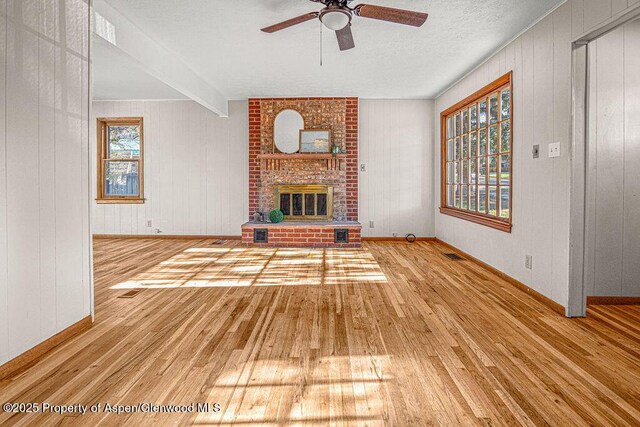 828 Taylor St, Craig, CO 81625 - unfurnished living room featuring hardwood / wood-style flooring, a ceiling fan, a brick fireplace, baseboards, and wooden walls