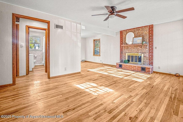 828 Taylor St, Craig, CO 81625 - unfurnished living room with wood finished floors, baseboards, ceiling fan, a textured ceiling, and a brick fireplace