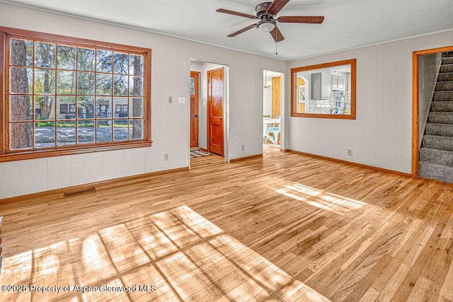 828 Taylor St, Craig, CO 81625 - unfurnished living room with wood finished floors, ceiling fan, baseboards, stairway, and a textured ceiling
