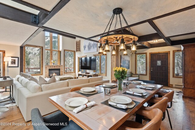 dining area with baseboard heating, a chandelier, beamed ceiling, and wood-type flooring