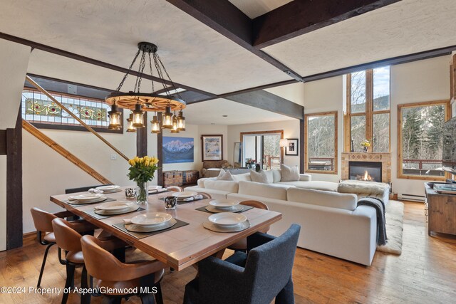 dining room featuring beam ceiling, an inviting chandelier, a baseboard radiator, and light wood-type flooring