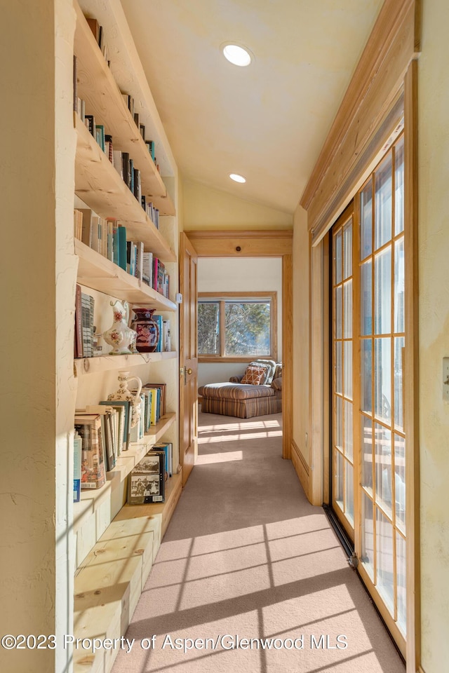 hallway with light carpet and lofted ceiling