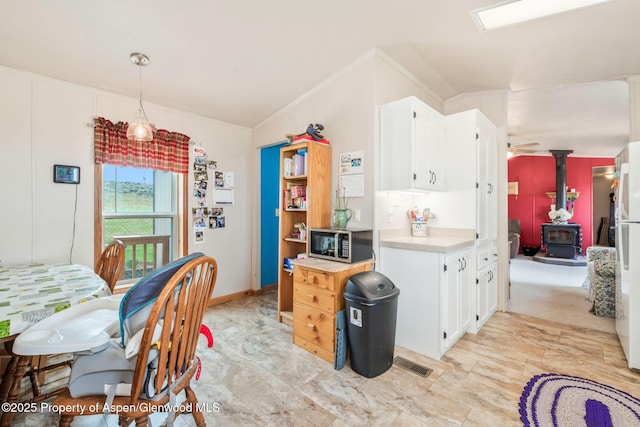 400 Behrman St, Craig, CO 81625 - kitchen featuring a wood stove, stainless steel microwave, light countertops, white cabinetry, and hanging light fixtures