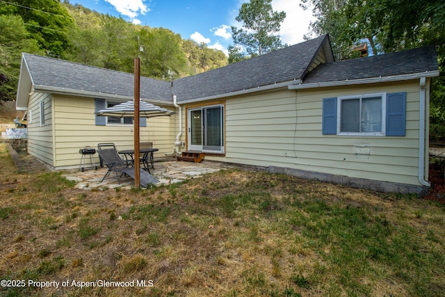 1026 Palmer Ave, Glenwood Springs, CO 81601 - rear view of property featuring a patio, a lawn, and a shingled roof