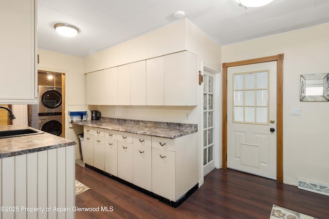 1026 Palmer Ave, Glenwood Springs, CO 81601 - kitchen featuring estacked washer and dryer, dark wood-style flooring, and white cabinetry