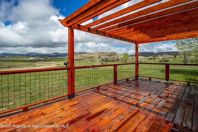 wooden deck with a mountain view, a yard, a pergola, and a rural view