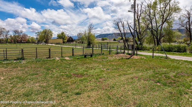 view of yard featuring a rural view, fence, and a mountain view