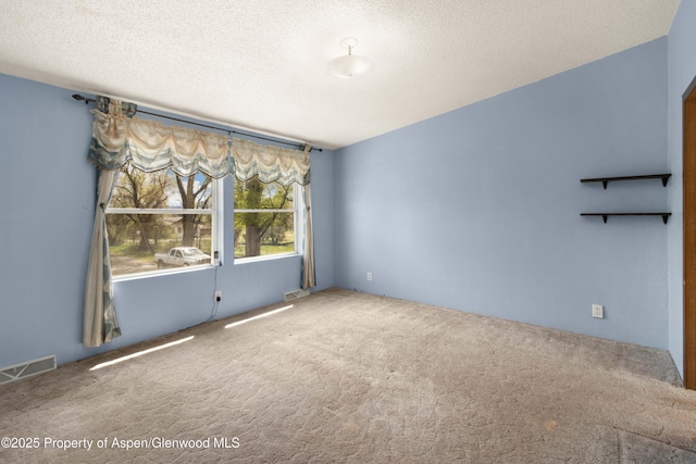 spare room with visible vents, carpet flooring, and a textured ceiling