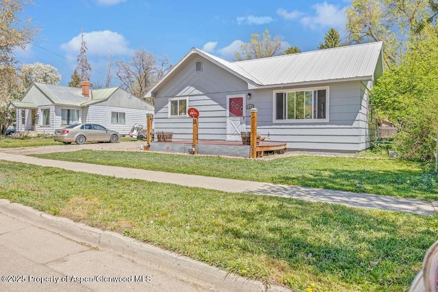 view of front of home with metal roof and a front lawn