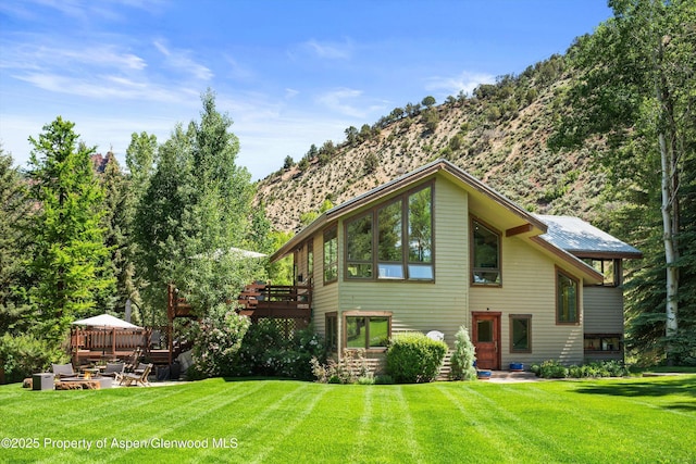 2755 Lower River Rd, Snowmass, CO 81654 - rear view of property with a fire pit, a lawn, and a deck with mountain view