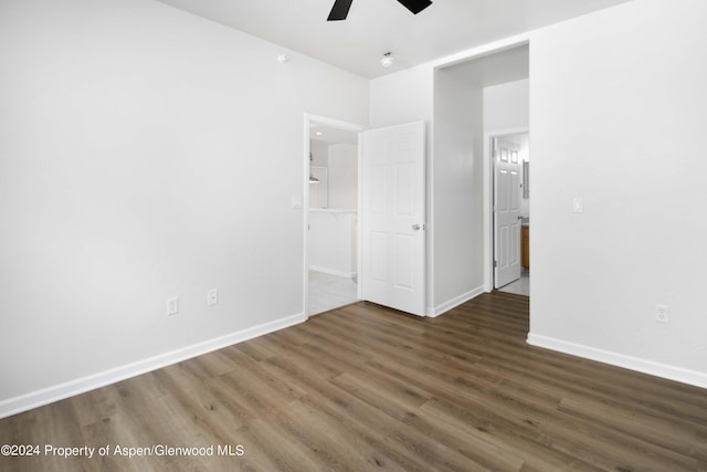 unfurnished bedroom featuring a walk in closet, dark hardwood / wood-style flooring, and ceiling fan