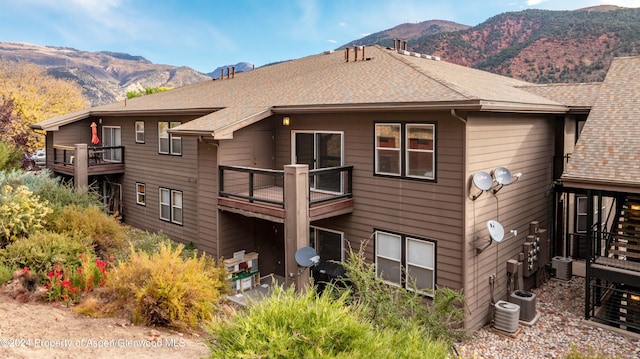 back of house featuring a mountain view, a balcony, and central AC unit