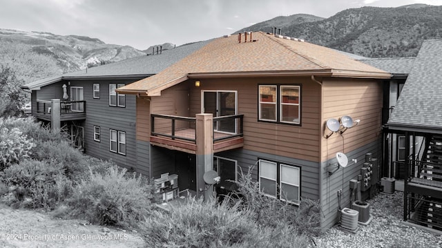 back of property with a mountain view, a balcony, and cooling unit