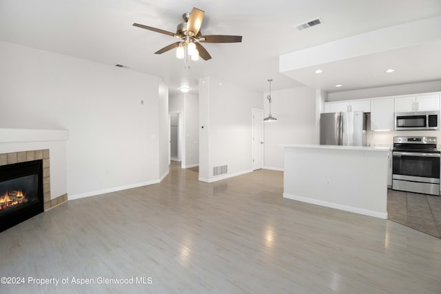 unfurnished living room with ceiling fan and a fireplace