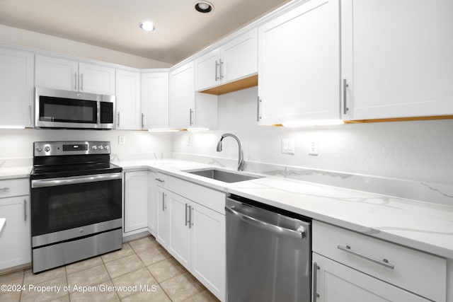 kitchen featuring sink, light tile patterned floors, light stone counters, white cabinetry, and stainless steel appliances