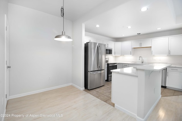 kitchen with appliances with stainless steel finishes, sink, light hardwood / wood-style flooring, white cabinets, and hanging light fixtures