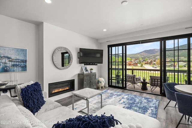 living room with a glass covered fireplace, recessed lighting, and wood finished floors