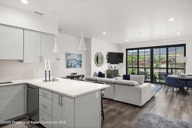 kitchen with a peninsula, light countertops, modern cabinets, dark wood-type flooring, and recessed lighting