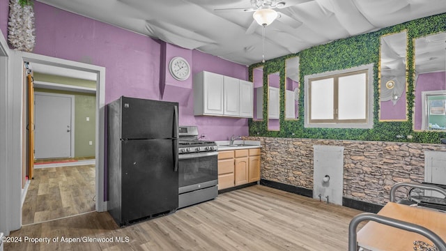 kitchen with ceiling fan, stainless steel gas stove, sink, light hardwood / wood-style floors, and black refrigerator