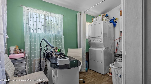 clothes washing area featuring hardwood / wood-style flooring and stacked washer / dryer